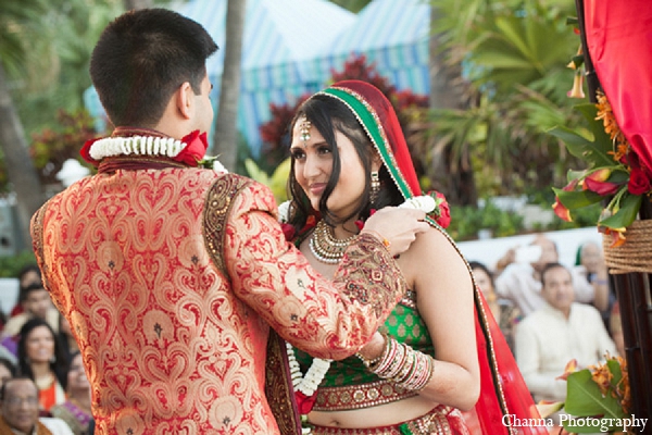 An Indian bride and groom wed in a beach side ceremony. The bride chooses a pink palette for both her sangeet reception outfits donning a anarkali suit and gown. She takes the traditional route for her bridal lengha.