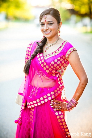 An Indian bride and groom celebrate their union with family and friends during a mehndi night, garba, traditional Hindu wedding ceremony, and reception. The bride dons lenghas in array of colors including hot pink, red, and white.