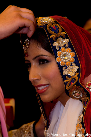 Traditional hair and makeup is fixed for the bride before the Indian wedding ceremony.