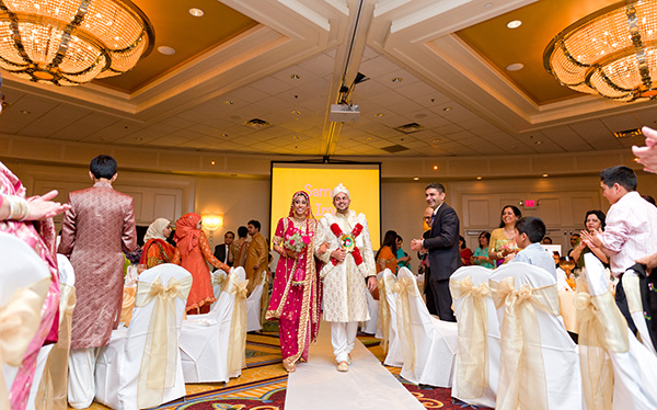 An Indian bride and groom walk into their Indian wedding reception.