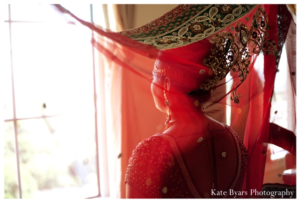 A red chuni is placed on this indian bride's head.