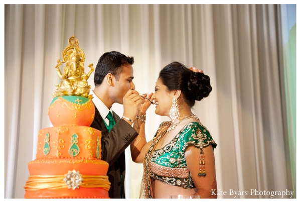 Indian bride and groom feed each other pieces of indian wedding cake.