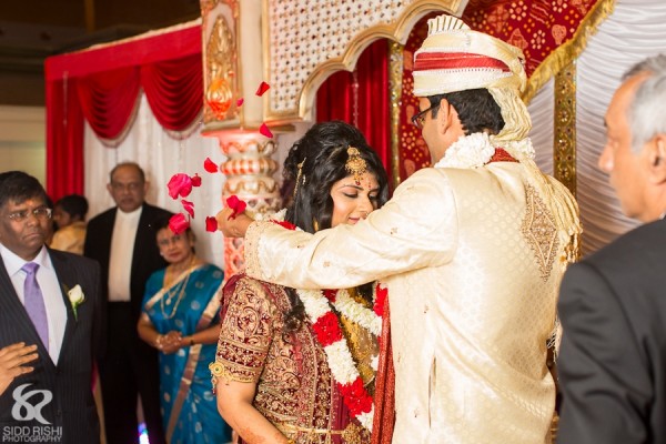 A groom puts a flower garland on his Indian bride.