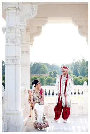 An indian bride and groom have their portrait taken at a hindu temple.