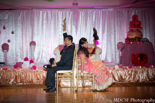 An Indian bride and groom play games at their modern pink Indian wedding reception.