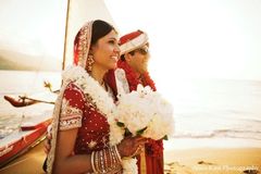 An Indian bride and groom take portraits along the beach at their Hawaiian wedding destination.