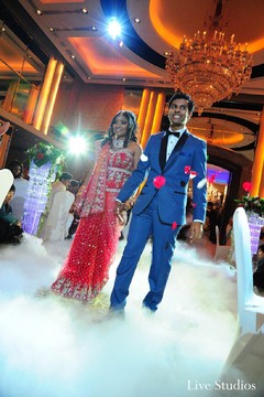 This Indian wedding reception features the bride in a stunning ruby red lengha and the groom in bright blue!