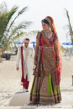 An Indian bride and groom take portraits on the beach.