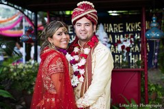 This Indian fusion wedding features a bride and groom in traditional red and cream outfits who are ready for their portrait session.