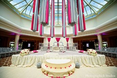 An Indian bride and groom wed in a Hindu ceremony under a pink and gray mandap.