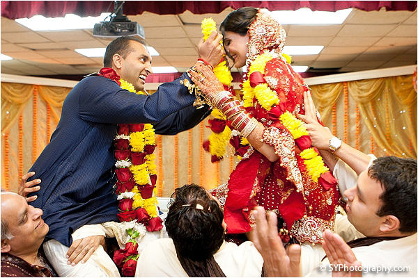 An Indian bride and groom give each other jaimalas, or flower wreaths.