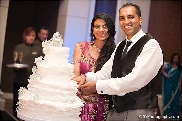 An Indian bride and groom cut into their grand Indian wedding cake.