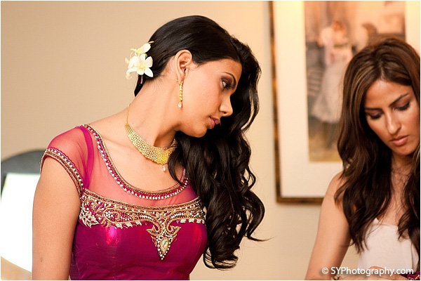 An Indian bride wears a hot pink bridal lengha as she prepares for her Indian wedding reception.