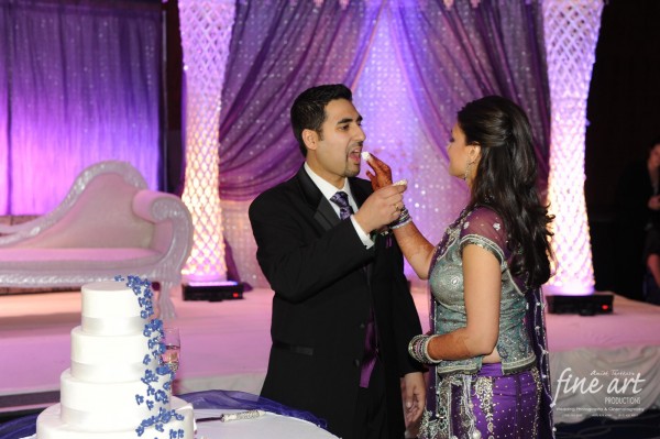 An indian bride and groom feed eachother their Indian wedding cake.