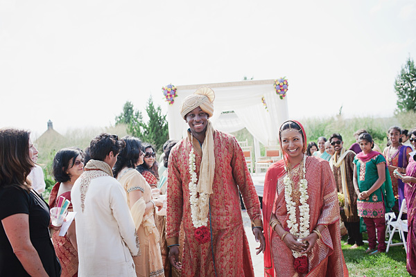 An Indian bride and groom are all smiles as they leave their Indian wedding ceremony.