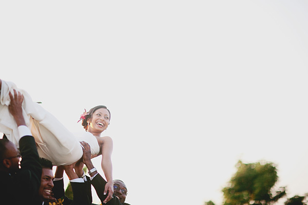 An Indian bride is hoisted over her groomsmen shoulders.