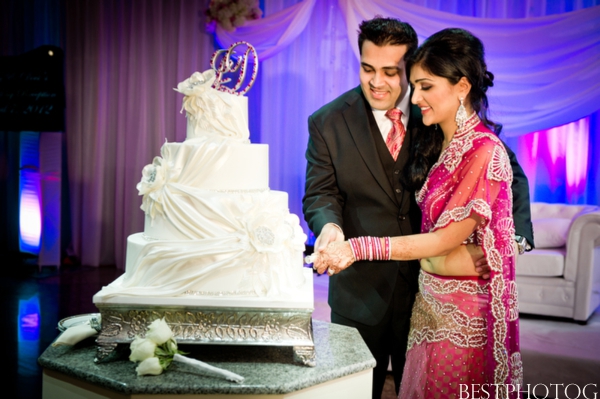 An Indian bride and groom cut into their Indian wedding cake.