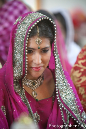 Sikh Indian bride in hot pink sari at wedding ceremony.