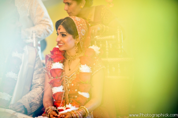 Indian bride wears traditional bridal lengha with jaimala flower garland.