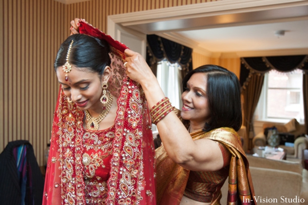 indian bride puts on indian wedding gown in red