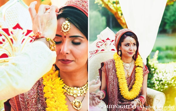 Indian bride wears red wedding lengha and yellow jaimala at indian wedding ceremony.