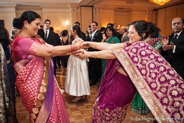 Indian wedding reception with guests dancing in wedding saris.