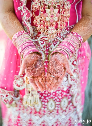 Indian bridal henna on hands on indian bride in pink wedding lengha